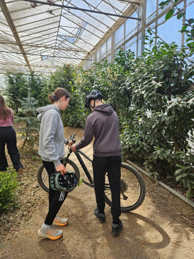 Participants walking with bicycles through a greenhouse during an international exchange visit