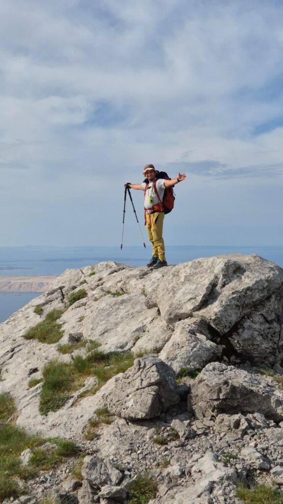 Hiker standing on a rocky peak on Velebit Mountain during the 12 Peaks – Challenge Up ascent
