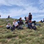 Participants of the 12 Peaks – Challenge Up project resting together on a grassy mountain ridge during a group hike on Velebit Mountain