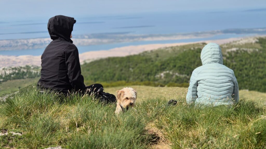 “Participants of the 12 Peaks – Challenge Up project resting in nature with a small dog while overlooking the Velebit landscape and the Adriatic coast