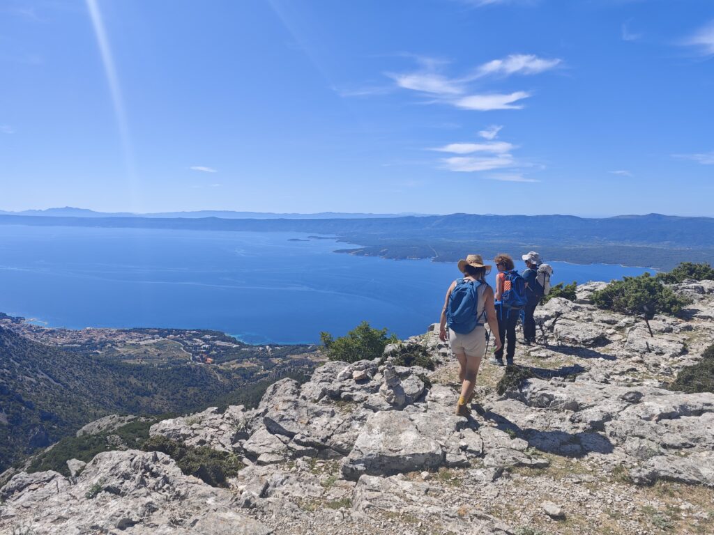 Hikers approaching the summit of Vidova Gora with panoramic views of the Adriatic Sea and nearby islands.