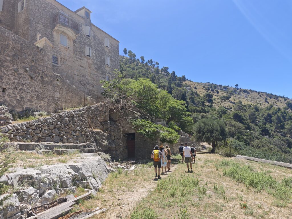 Participants of the 12 Peaks Challenge Up project walking through the historic grounds of Blaca Hermitage on Brač Island, Croatia.